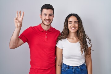 Young hispanic couple standing over isolated background showing and pointing up with fingers number three while smiling confident and happy.