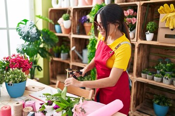 Young beautiful arab woman florist cutting plant at flower shop