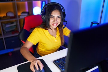 Young beautiful arab woman streamer smiling confident sitting on table at gaming room