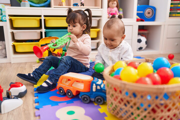 Adorable boy and girl playing trumpet holding balls at kindergarten © Krakenimages.com