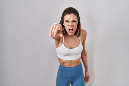 Hispanic woman wearing sportswear over isolated background pointing displeased and frustrated to the camera, angry and furious with you - Powered by Adobe