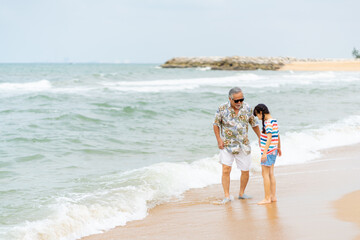 Happy Asian family travel ocean on summer holiday vacation. Grandfather and grandchildren girl...