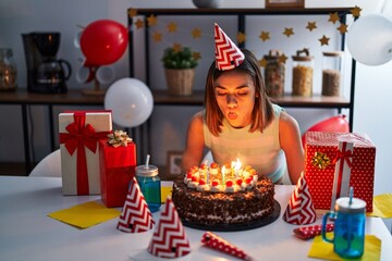 Young beautiful hispanic woman celebrating birthday blowing candle at home