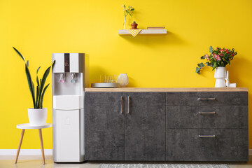 Interior of kitchen with modern water cooler near yellow wall