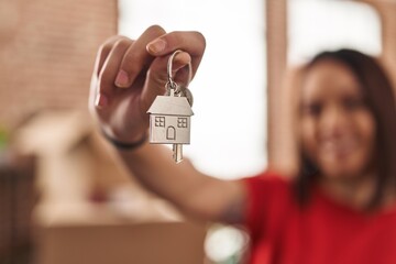 Young beautiful hispanic woman smiling confident holding key at new home