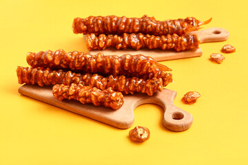 Wooden boards with tasty churchkhela on yellow background