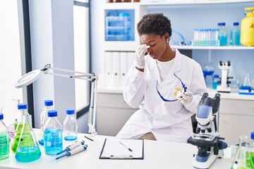 African american woman wearing scientist uniform stressed working at laboratory