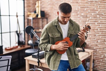 Young hispanic man musician playing ukelele at music studio