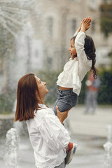 Fototapeta premium Mom and her little daughter playing by the spray of water