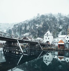 Vertical shot of the river reflecting the houses and the snow-covered mountains, Kelheim, Germany