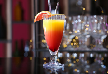 Glass of tasty Tequila Sunrise with grapefruit slice on table in bar