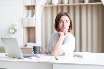 Young female student sitting at the desk at home and preparing for a new academic year. Education and online training concept