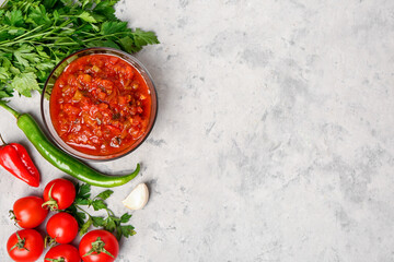 Composition with bowl of delicious salsa sauce and ingredients on grey grunge background
