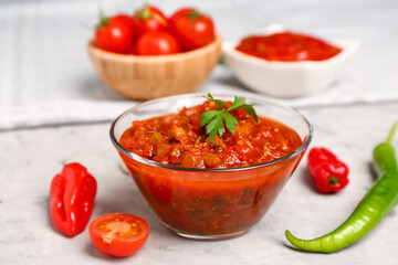 Bowl of delicious salsa sauce on grey grunge table, closeup