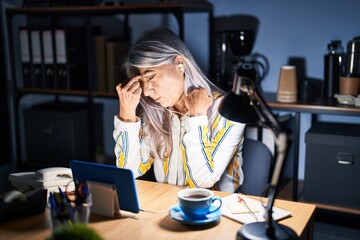 Middle age woman with grey hair working at the office at night tired rubbing nose and eyes feeling fatigue and headache. stress and frustration concept.