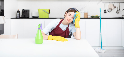 Tired woman sitting in the kitchen after cleaning house	
