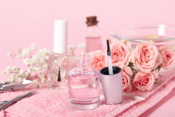 Composition with bottles of cuticle oil, manicure instruments and flowers on pink background, closeup