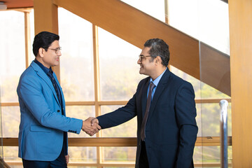 Two indian businessman shake hand at office.