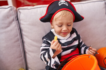 Adorable caucasian boy wearing pirate costume eating sweet at home