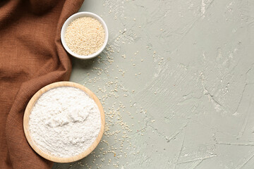 Bowls with wheat flour and sesame seeds on grey grunge table