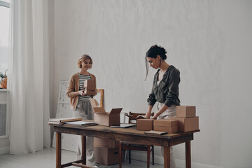 Two confident businesswomen preparing packages for delivery in warehouse