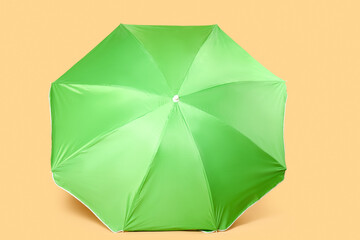 Green beach umbrella on beige background