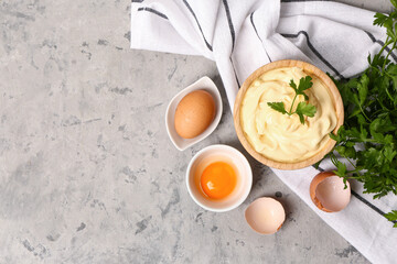 Bowl with tasty mayonnaise sauce, eggs and parsley on grunge background
