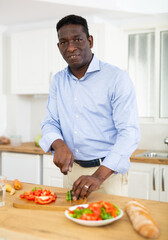 Fototapeta na wymiar Adult man preparing vegetable salad for dinner at home kitchen