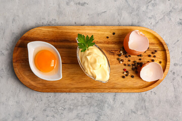 Gravy boat with tasty mayonnaise sauce and ingredients on grunge background