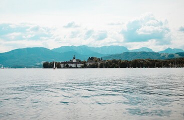 Calm lake with the big mountains and the Schloss Ort castle in the background in Gmunden, Austria