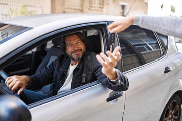Middle age man smiling confident holding key of new car at street