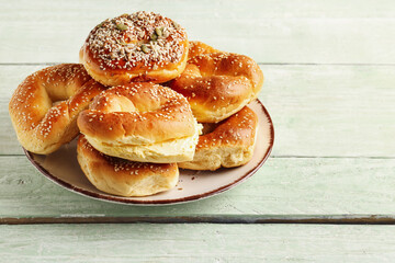 Plate of tasty bagels with sesame and cream cheese on green wooden background