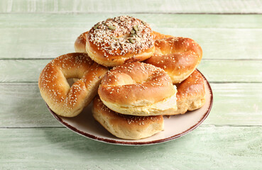 Plate of tasty bagels with sesame and cream cheese on green wooden background
