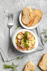 Bowl of tasty Olivier salad on light background