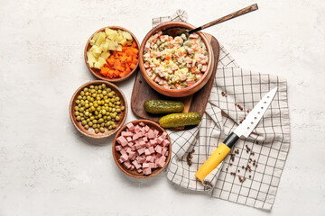 Bowl of tasty Olivier salad and ingredients on light background