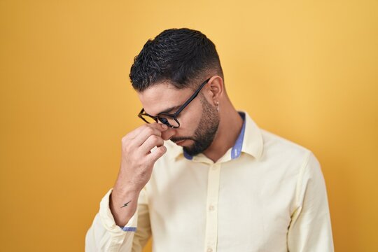 Hispanic young man wearing business clothes and glasses tired rubbing nose and eyes feeling fatigue and headache. stress and frustration concept.
