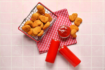 Basket with tasty nuggets and ketchup on pink tile background