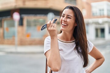 Young beautiful hispanic woman smiling confident listening audio message by the smartphone at street