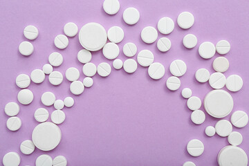 Frame made of white pills on lilac background