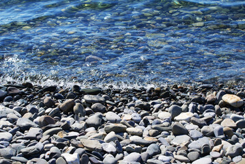 Seashore, sun glare on the water, pebbles on the seabed, nature. Background.