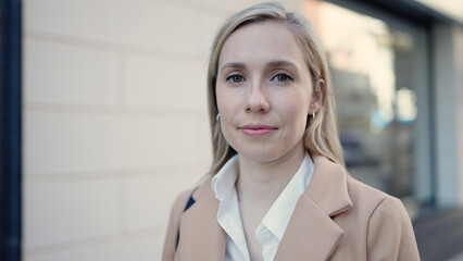Fototapeta premium Young blonde woman standing with serious expression at street