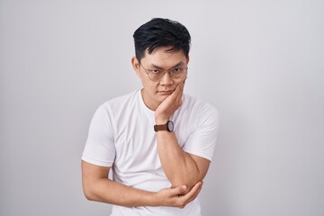 Young asian man standing over white background thinking looking tired and bored with depression...