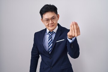 Young asian man wearing business suit and tie doing italian gesture with hand and fingers confident expression