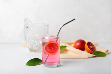 Glass of tasty blood orange lemonade on light background