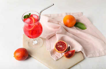 Glass of tasty blood orange lemonade and fresh fruits on light background