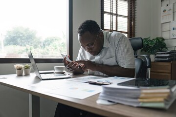 African American man calculating using machine managing household finances at home, focused biracial male make calculations on calculator account taxes or expenses