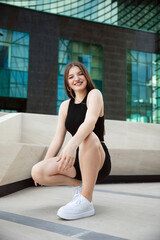 Fototapeta premium Front image of a gorgeous young woman in black top and shorts, posing with attitude outside.