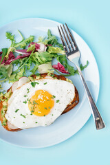 Delicious sandwich with fried egg and salad on blue background