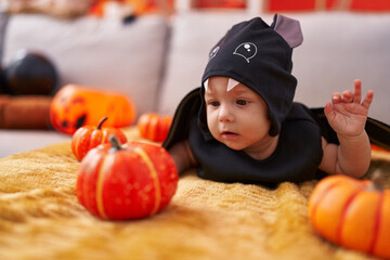 Fototapeta premium Adorable caucasian baby wearing bat costume lying on sofa at home
