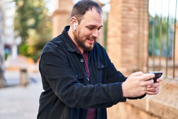 Young hispanic man smiling confident playing video game at street